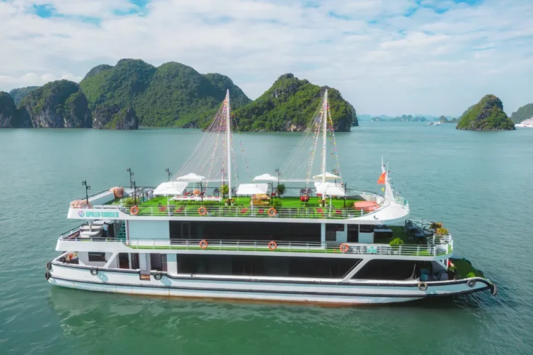 Apollo Halong Bay Day Cruise Tour boat sailing past limestone karsts under clear blue sky