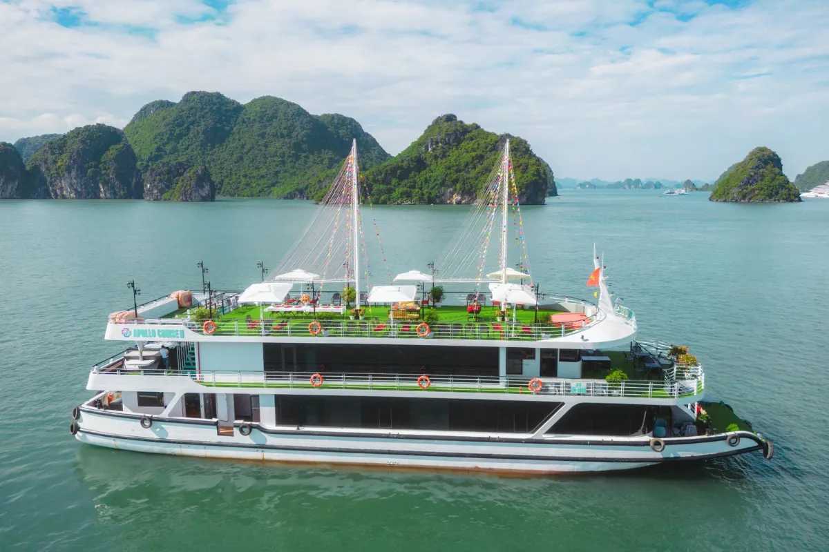 Apollo Halong Bay Day Cruise Tour boat sailing past limestone karsts under clear blue sky