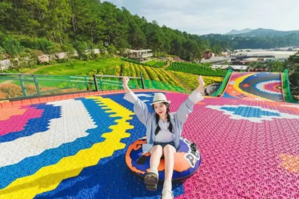 A woman sitting on a colorful inflatable tube slide at a flower garden park in Da Lat
