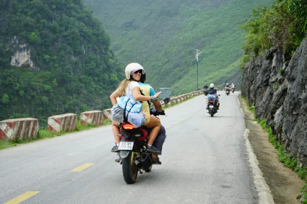 Travelers riding a motorbike along a winding mountain pass road on the Ha Giang Loop