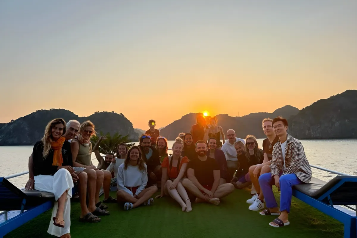 A large group of travelers gathered on a cruise sundeck watching the sunset while extending their route into Lan Ha Bay