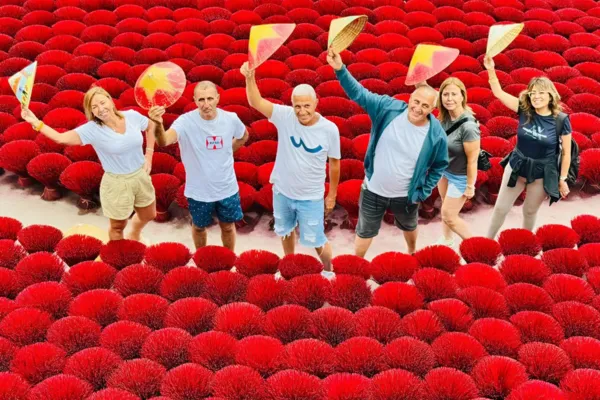 Tourists holding colorful conical hats amid rows of red incense sticks at Quang Phu Cau village near Hanoi