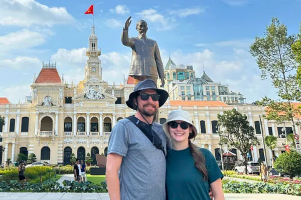 Two travelers posing in front of Ho Chi Minh City Hall and the Uncle Ho statue on Nguyen Hue Boulevard
