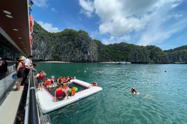 Cruise passengers swimming and relaxing at a floating platform beside limestone islands in Lan Ha Bay