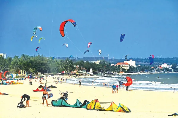 Kitesurfers with colorful kites on the beach and in the water at Mui Ne