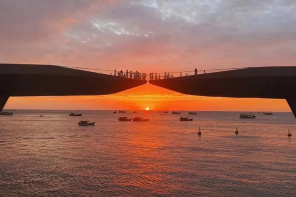Silhouettes of tourists on a bridge watching the sun set over the ocean in Phu Quoc