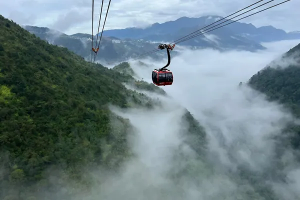 A cable car gondola crossing through clouds over green mountains near Sapa