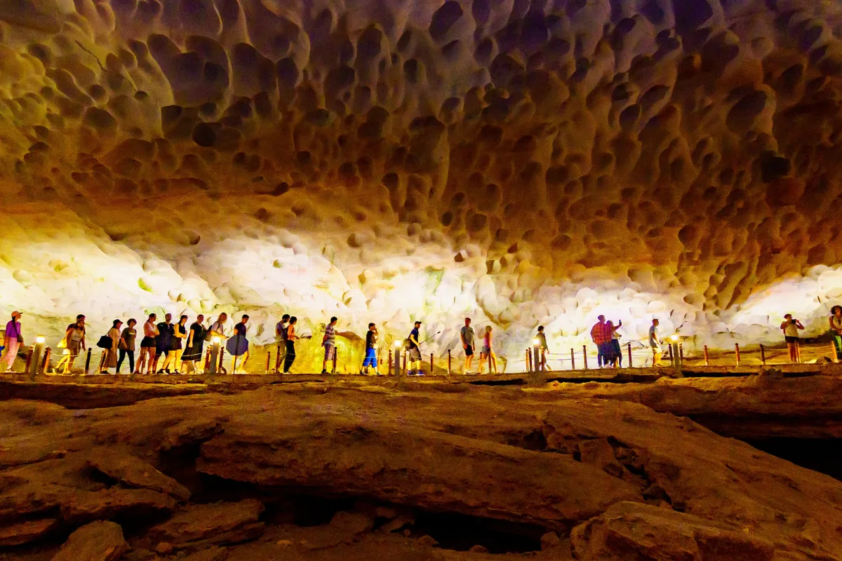 Tourists walking through the illuminated stalactite chambers inside Sung Sot Cave in Halong Bay