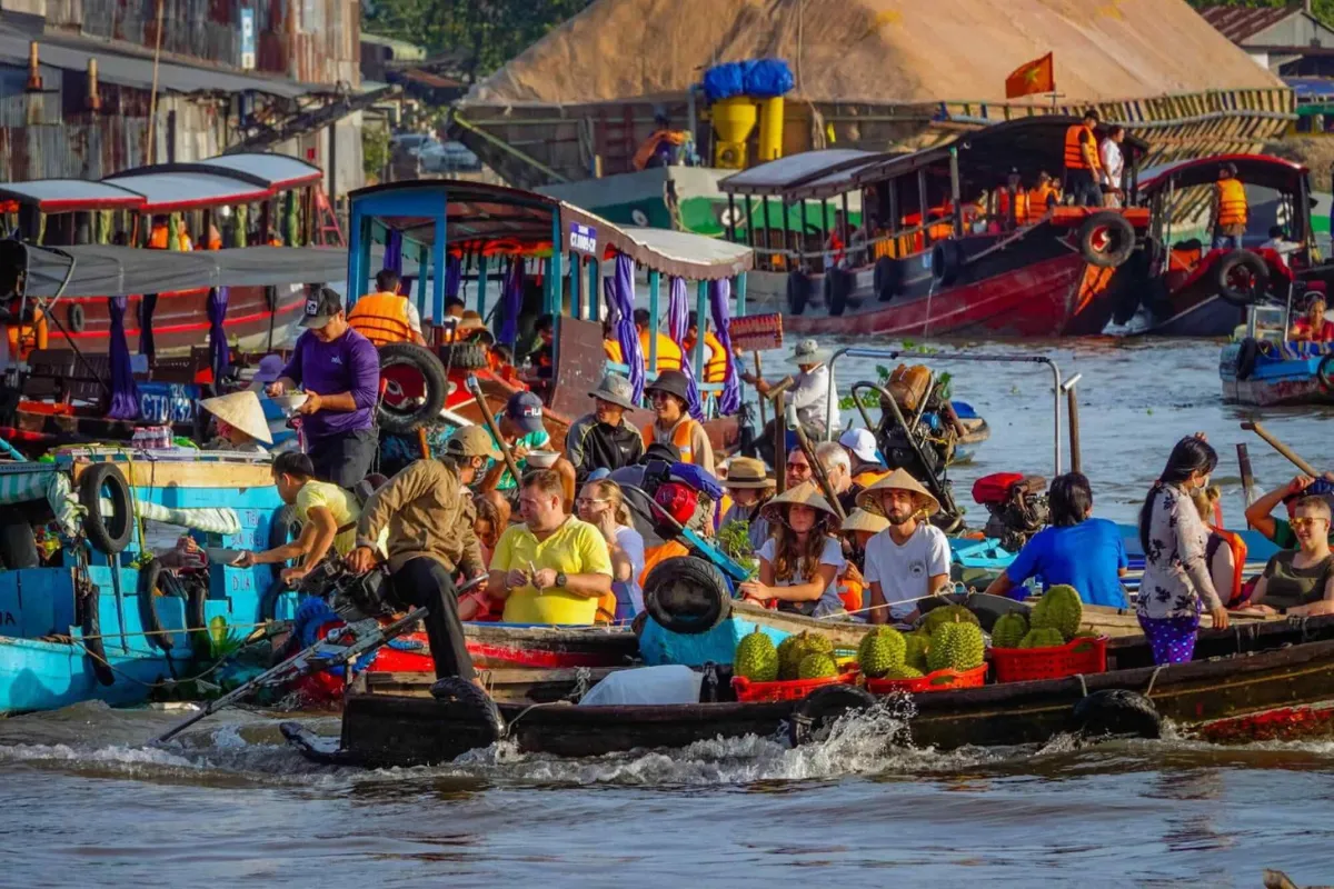 Tourist boats loaded with durian passing through the crowded Cai Be floating market on the Mekong Delta