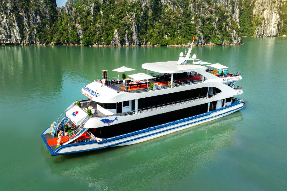 Aerial view of Harmony cruise ship gliding past towering limestone karsts on the Harmony Halong Bay day cruise tour