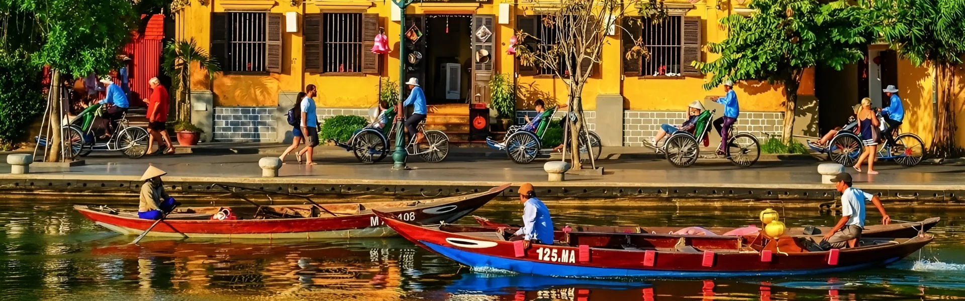 Traditional boats and cyclos along the riverside in front of yellow heritage buildings in Hoi An Ancient Town