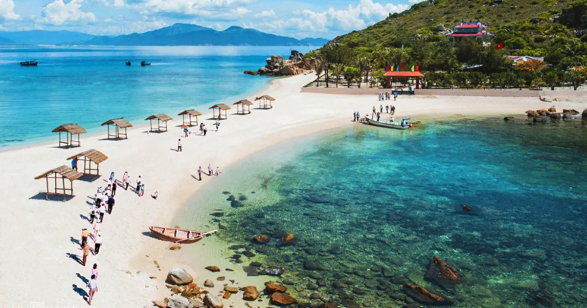 Aerial view of a white sand cove with thatched umbrellas and clear turquoise water in Nha Trang