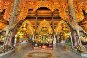 Three golden Buddha statues seated in a row inside Tam The Hall at Bai Dinh Pagoda, Ninh Binh