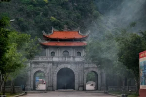 Stone gateway of Hoa Lu Ancient Citadel framed by misty limestone mountains in Ninh Binh Province