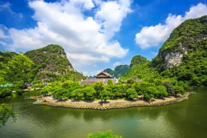 Aerial view of a temple complex and curved wooden boat dock surrounded by karst peaks at Trang An, Ninh Binh