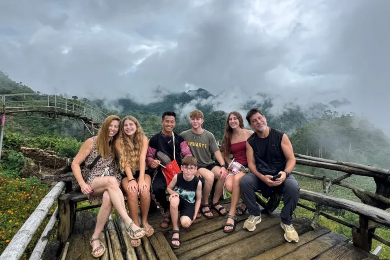 About Us 22 Family posing on a wooden viewing platform overlooking misty mountains at Pa Co clouds viewpoint near Mai Chau