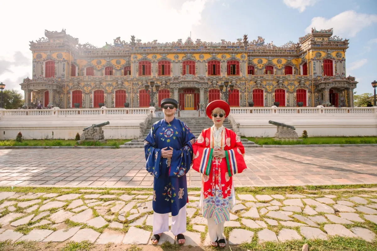 Couple dressed in colorful Nguyen Dynasty royal costumes in front of Kien Trung Palace, Hue