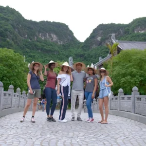 Tour group wearing conical hats on a stone bridge on Trang An Bai Dinh Pagoda Tour
