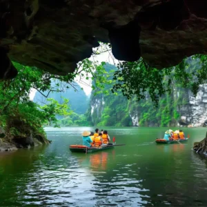 View from beneath a cave overhang of sampans carrying tourists through the Trang An boat tour waterway