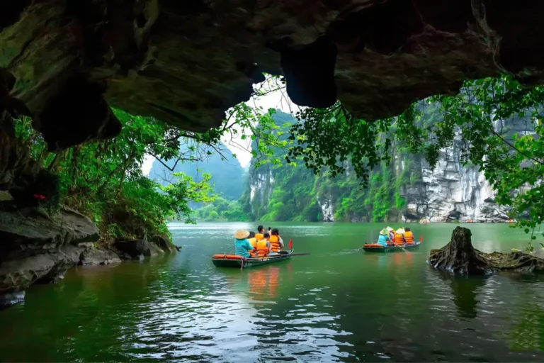 View from beneath a cave overhang of sampans carrying tourists through the Trang An boat tour waterway