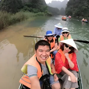 Tourists in life jackets take a boat selfie on the Trang An Hoa Lu tour river