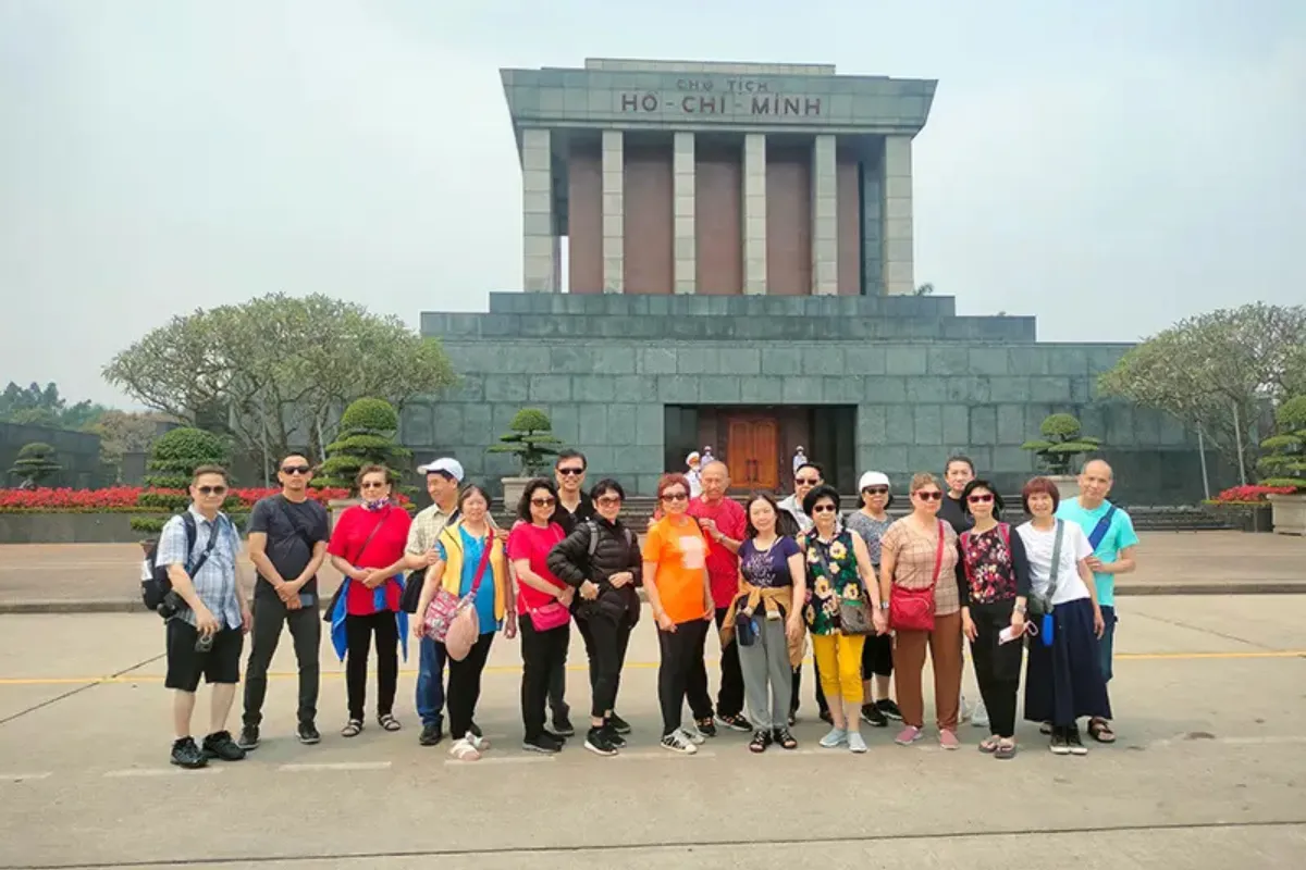 Large tour group posing in front of Ho Chi Minh Mausoleum on a Hanoi city tour half day