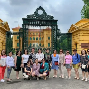 Group of tourists posing at the yellow Presidential Palace gate in Hanoi's Ho Chi Minh Complex