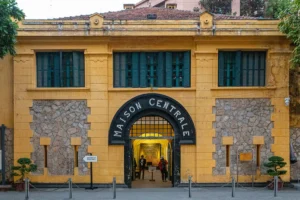 Yellow colonial facade of Hoa Lo Prison, labeled Maison Centrale, a historic Hanoi travel destination
