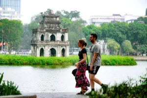 Couple walking beside Hoan Kiem Lake with Turtle Tower visible, a central Hanoi must-visit place