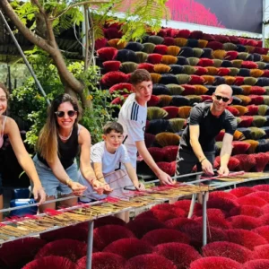 Family bundling incense sticks by hand at a workshop table during a Hanoi incense village tour