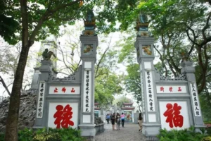 Ornate stone gate of Ngoc Son Temple with red Chinese characters, Hoan Kiem Lake, Hanoi