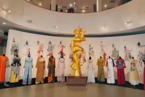 Golden maternal statue and rows of ao dai dresses on display at the Vietnamese Women's Museum, Hanoi